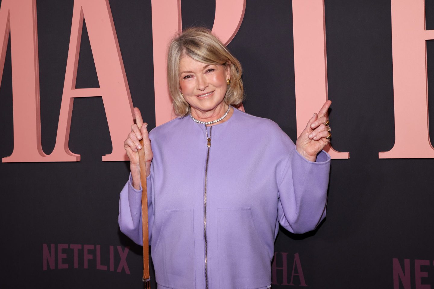 Martha Stewart in purple shirt in front of a netflix backdrop