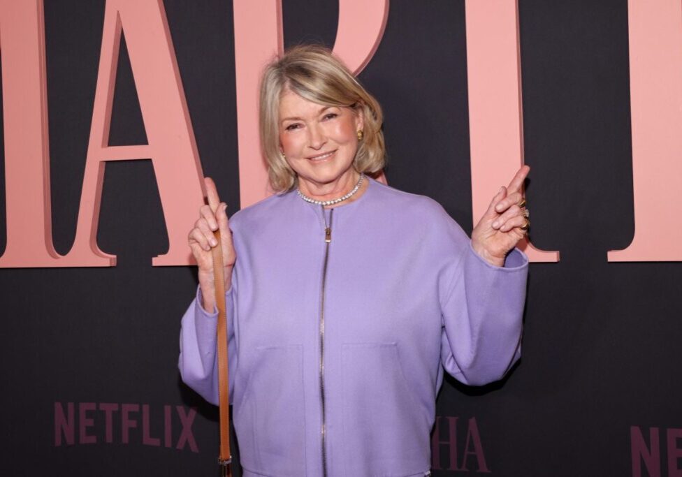 Martha Stewart in purple shirt in front of a netflix backdrop